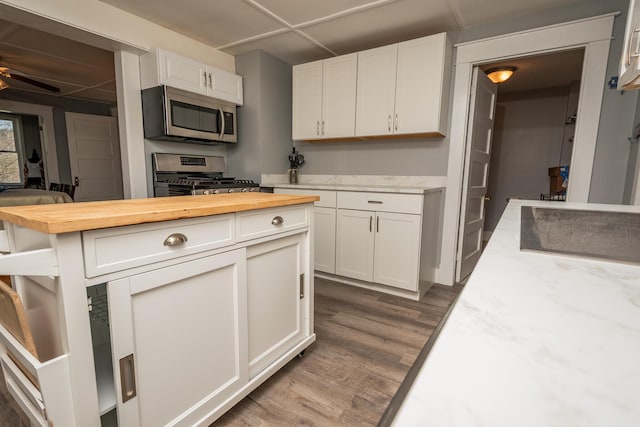 kitchen with white cabinets, wooden counters, stainless steel appliances, and dark wood-type flooring