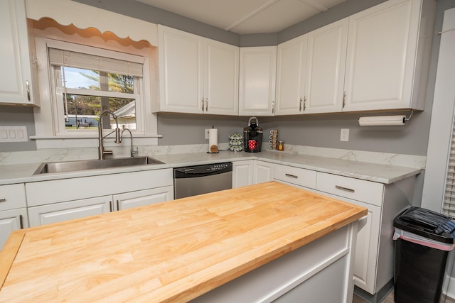 kitchen with butcher block countertops, white cabinetry, a sink, and dishwasher