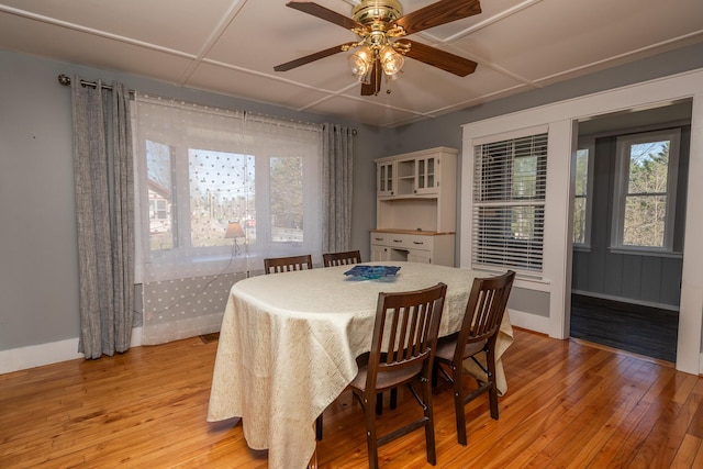 dining area featuring light wood finished floors, baseboards, a ceiling fan, and plenty of natural light