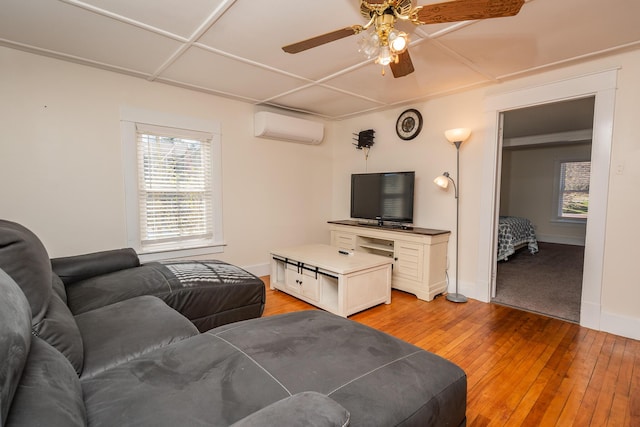living area with ceiling fan, light wood-style flooring, a wall mounted AC, and a healthy amount of sunlight