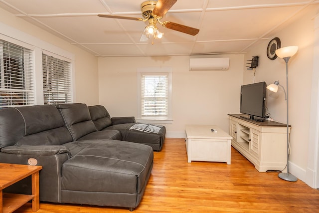 living room with baseboards, light wood finished floors, ceiling fan, and a wall mounted AC