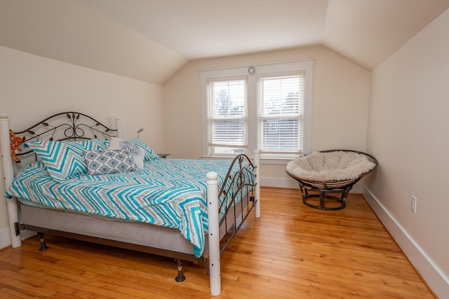 bedroom with lofted ceiling, baseboards, and light wood-type flooring
