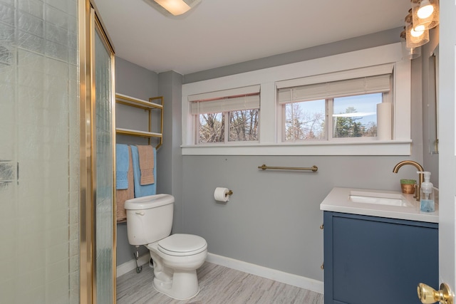 bathroom featuring toilet, baseboards, vanity, and a shower