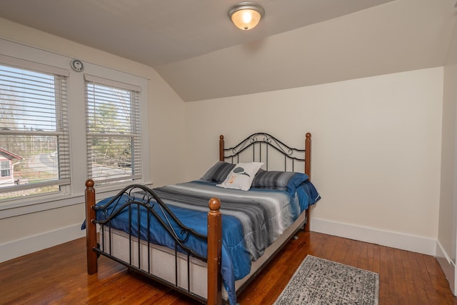 bedroom with vaulted ceiling, hardwood / wood-style flooring, and baseboards