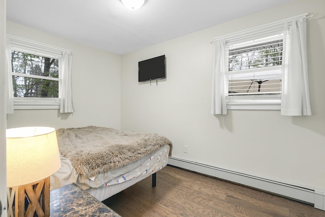 bedroom with a baseboard radiator, multiple windows, and wood finished floors