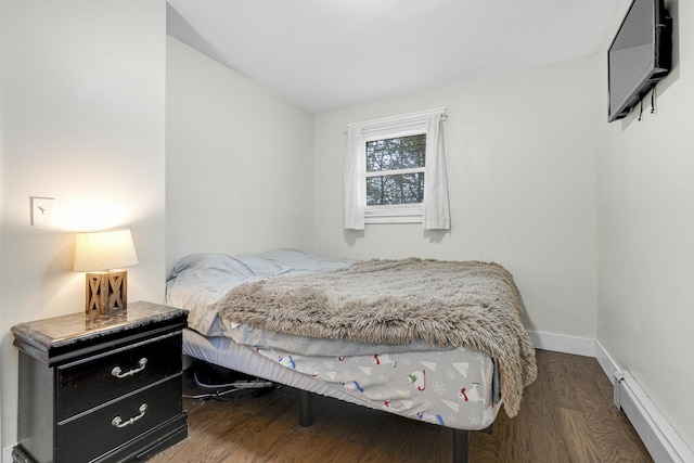 bedroom with a baseboard radiator, wood finished floors, and baseboards