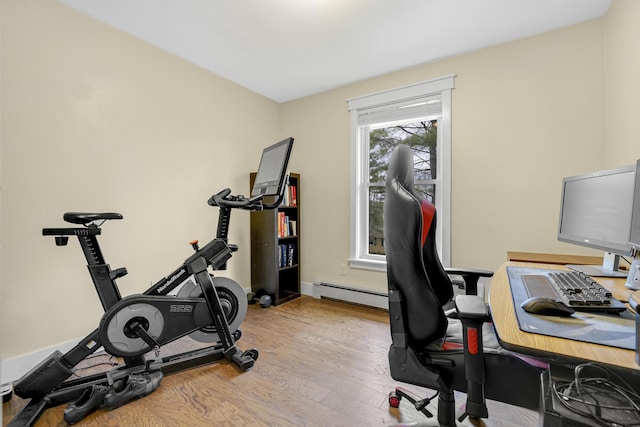 workout room featuring wood finished floors, a baseboard radiator, and baseboards