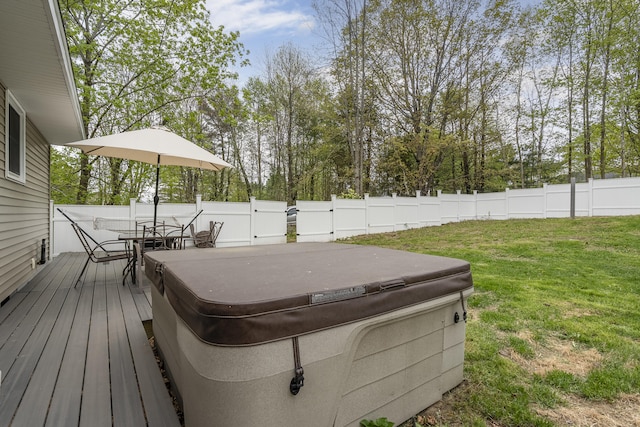 wooden deck featuring a hot tub, outdoor dining space, and view of wooded area