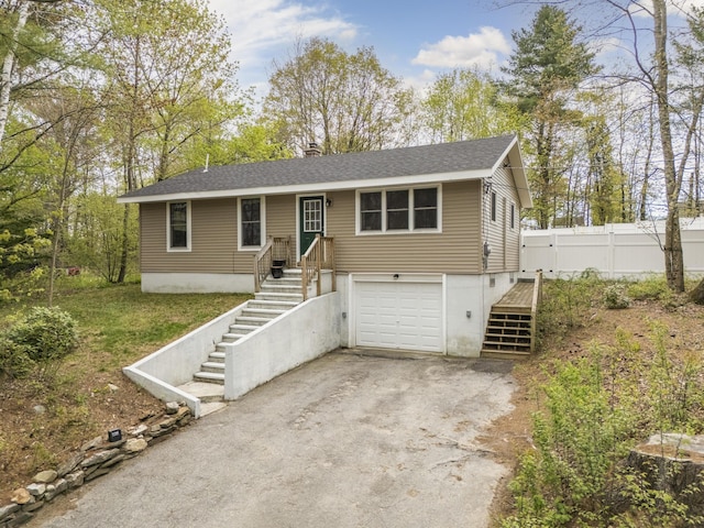 view of front of home featuring stairway, asphalt driveway, a garage, a chimney, and fence