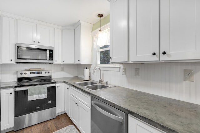 kitchen with appliances with stainless steel finishes, a sink, white cabinets, and dark wood-type flooring