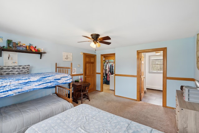 bedroom with carpet flooring, a walk in closet, ceiling fan, a closet, and baseboards
