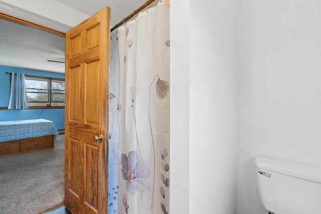 bathroom with toilet, a shower with shower curtain, and baseboard heating