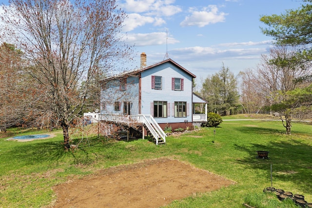 back of house with a chimney, a lawn, stairs, and a deck
