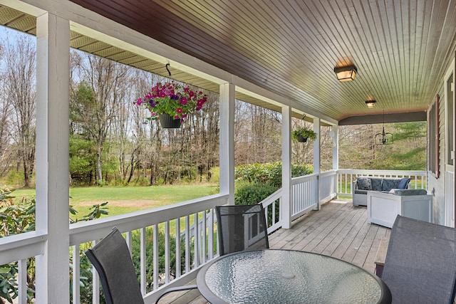 wooden deck with covered porch, outdoor dining area, and a lawn
