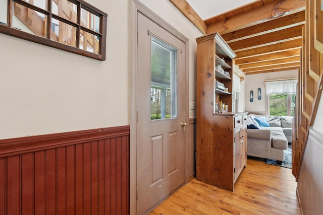 doorway featuring light wood finished floors and beam ceiling