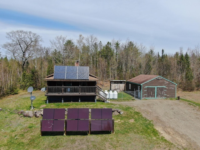 111 Fryes Ln, Greenbush, ME 04418 - rear view of house with driveway, solar panels, a garage, and a forest view