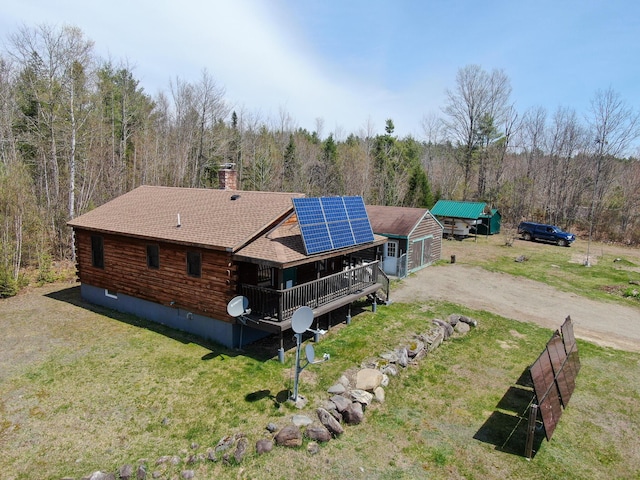 111 Fryes Ln, Greenbush, ME 04418 - rear view of property featuring log siding, solar panels, a view of trees, a shingled roof, and driveway
