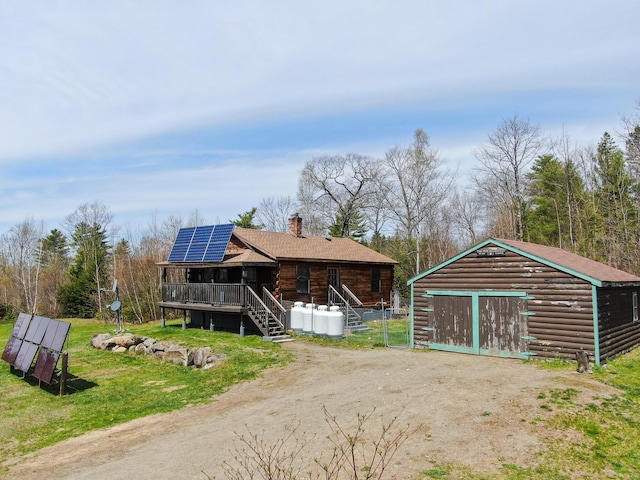 111 Fryes Ln, Greenbush, ME 04418 - view of front of property with an outdoor structure, a chimney, solar panels, a shingled roof, and a deck