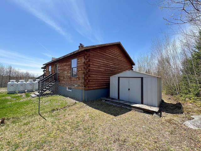 111 Fryes Ln, Greenbush, ME 04418 - view of home's exterior featuring log siding, a storage shed, an outbuilding, and a chimney