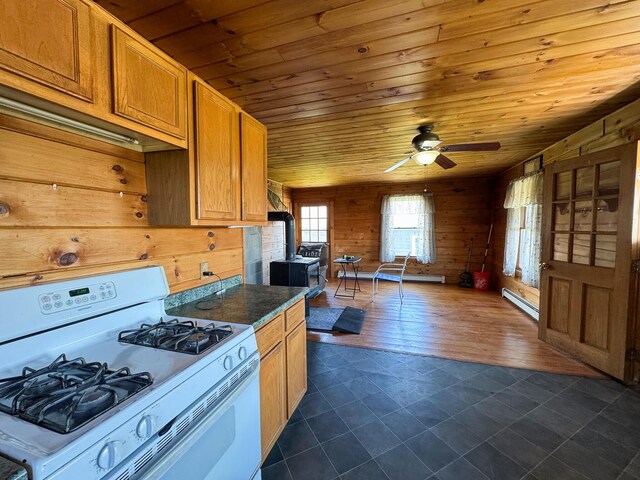 111 Fryes Ln, Greenbush, ME 04418 - kitchen with white range with gas stovetop, wooden ceiling, wood walls, dark tile patterned flooring, and baseboard heating