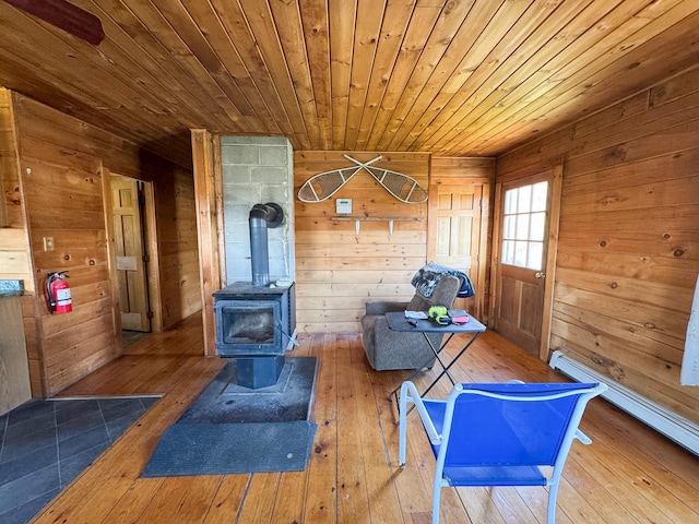 111 Fryes Ln, Greenbush, ME 04418 - workout room with hardwood / wood-style floors, a baseboard radiator, wooden ceiling, wooden walls, and a wood stove