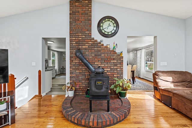 48 Albion Rd, Windham, ME 04062 - living room featuring a wood stove, light wood-type flooring, plenty of natural light, vaulted ceiling, and a baseboard heating unit