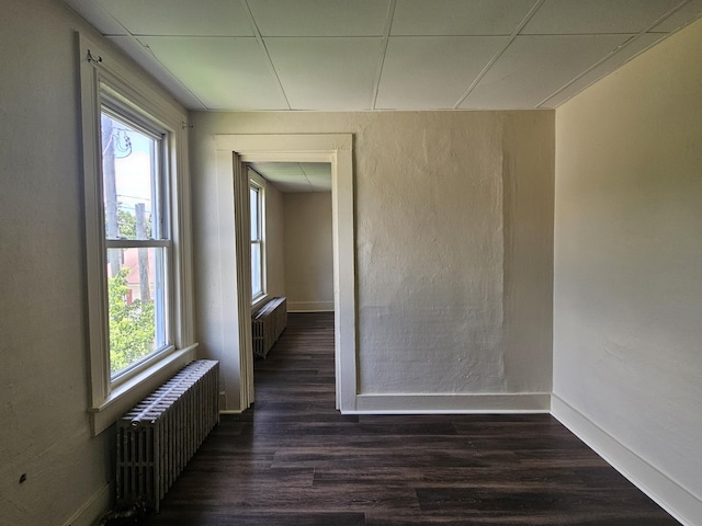 spare room with radiator heating unit, dark wood-style flooring, and plenty of natural light