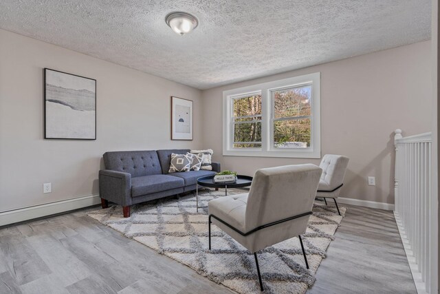living area with wood finished floors, a textured ceiling, baseboards, and a baseboard radiator
