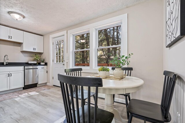 dining space featuring light wood-type flooring, a textured ceiling, and baseboards