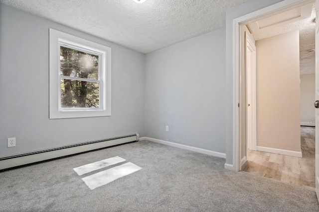 spare room featuring a textured ceiling, carpet, a baseboard radiator, and baseboards