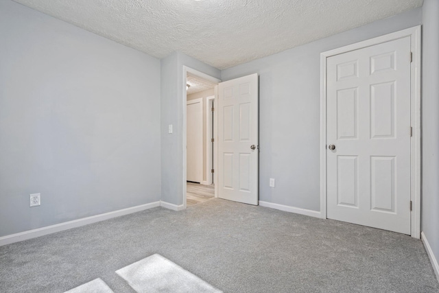 unfurnished bedroom featuring carpet flooring, a textured ceiling, and baseboards