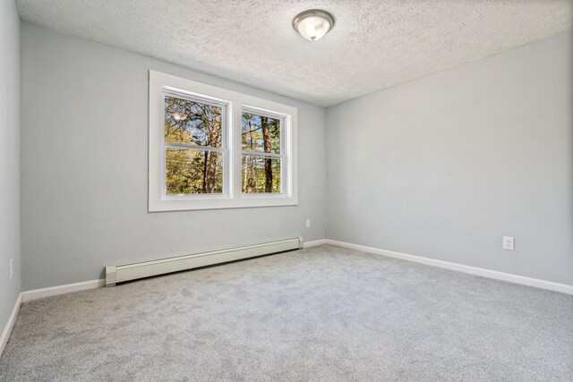 empty room featuring baseboard heating, a textured ceiling, carpet floors, and baseboards