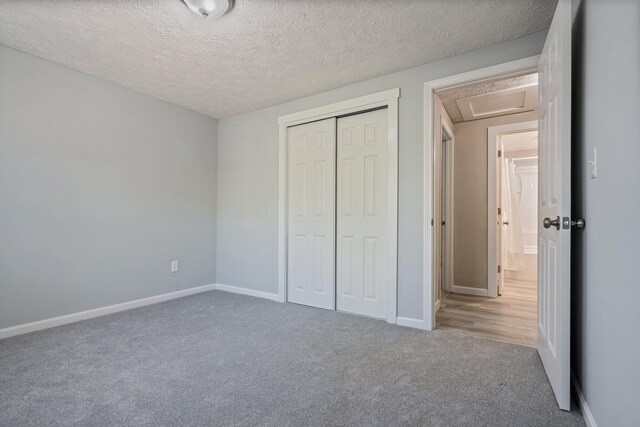 unfurnished bedroom with carpet flooring, a closet, baseboards, and a textured ceiling