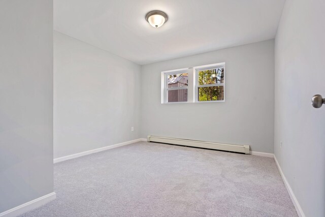 carpeted spare room with a baseboard radiator and baseboards