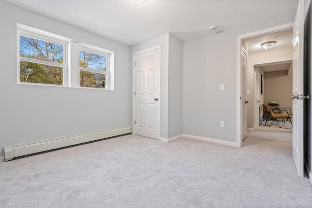 unfurnished bedroom with baseboard heating, light colored carpet, and baseboards