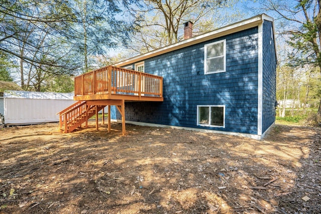 rear view of house with a deck, a chimney, and stairway