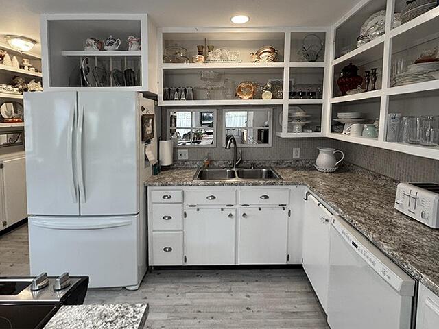 kitchen with open shelves, white cabinetry, a sink, and white appliances