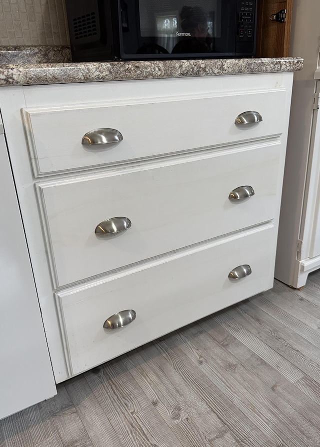 details with black microwave and wood finished floors