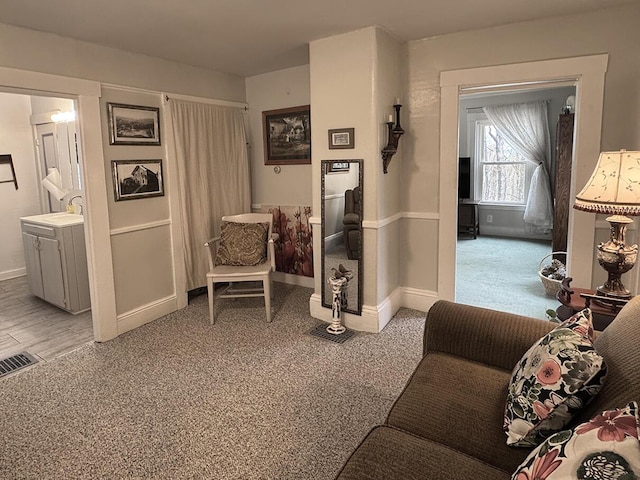 hall with light colored carpet, visible vents, baseboards, and a sink