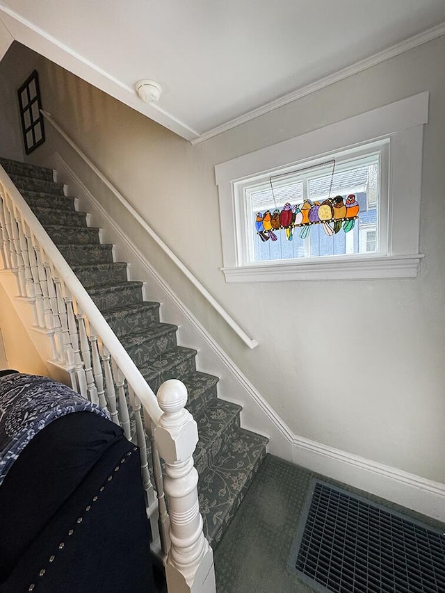 stairway featuring ornamental molding, a wealth of natural light, and visible vents