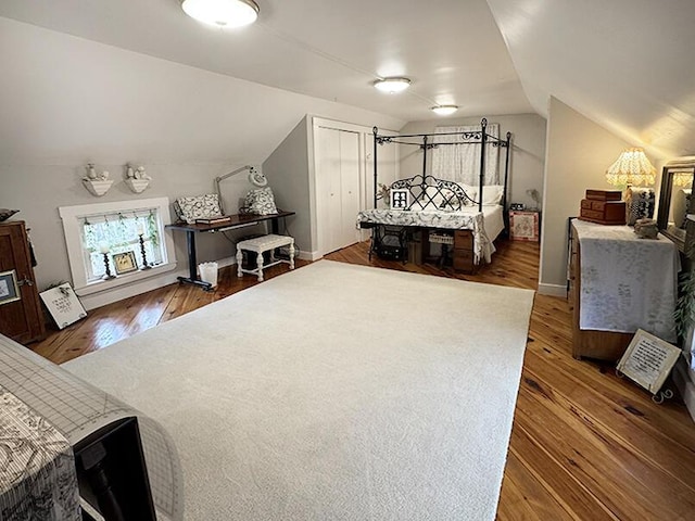 bedroom featuring baseboards, hardwood / wood-style floors, and vaulted ceiling