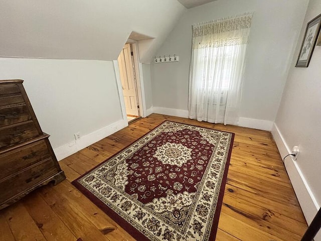 additional living space with lofted ceiling, hardwood / wood-style flooring, and baseboards