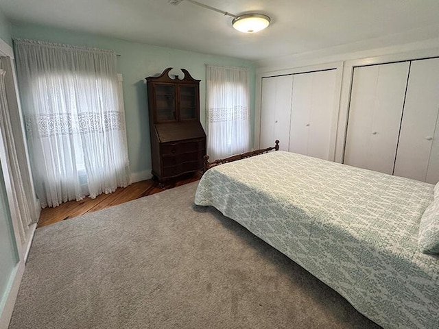bedroom featuring wood finished floors, baseboards, and multiple closets