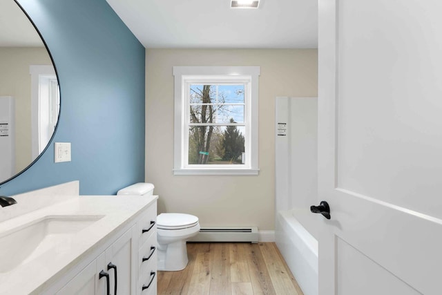 26 June St, Sanford, ME 04073 - bathroom with baseboard heating, wood finished floors, toilet, vanity, and a bath