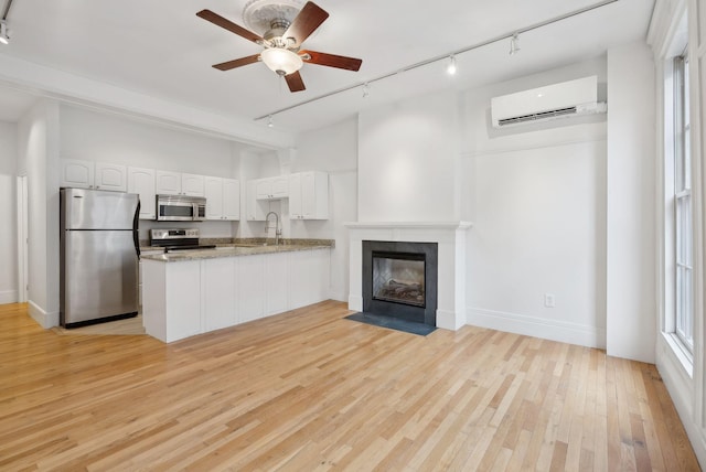 17 Pine St Unit 1, Portland, ME 04102 - kitchen featuring appliances with stainless steel finishes, rail lighting, a wall unit AC, a sink, and a peninsula