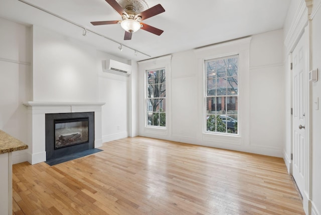 17 Pine St Unit 1, Portland, ME 04102 - unfurnished living room featuring rail lighting, a wall mounted air conditioner, light wood-type flooring, a fireplace with flush hearth, and ceiling fan