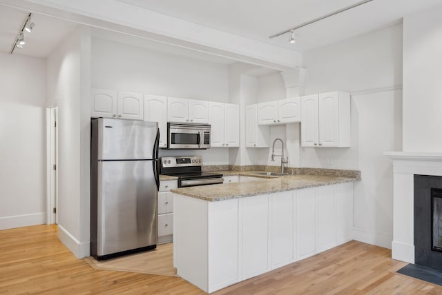 17 Pine St Unit 1, Portland, ME 04102 - kitchen with rail lighting, appliances with stainless steel finishes, a sink, a peninsula, and white cabinets