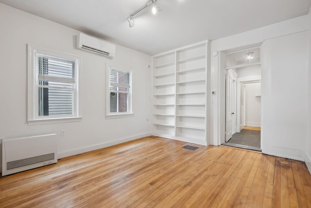 17 Pine St Unit 1, Portland, ME 04102 - spare room featuring a wall unit AC, built in shelves, light wood finished floors, heating unit, and baseboards