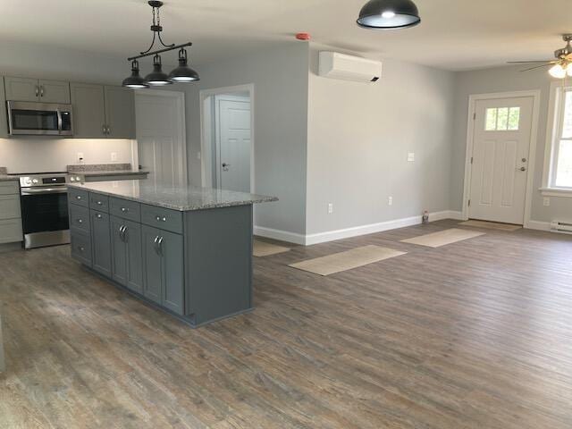 kitchen with baseboards, dark wood finished floors, stainless steel microwave, and an AC wall unit