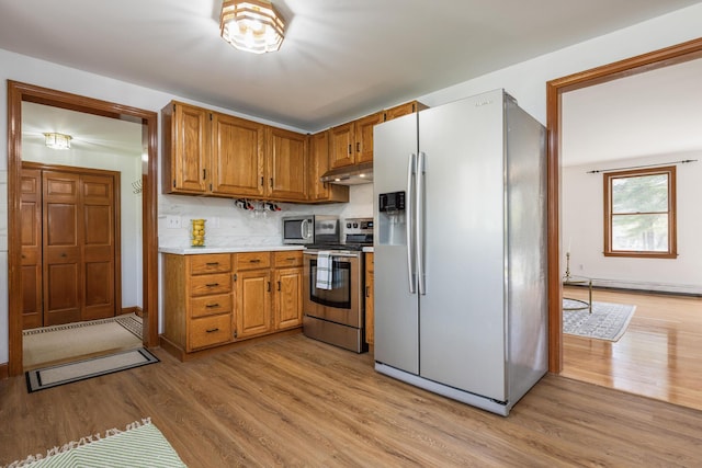 784 Ocean Ave, Portland, ME 04103 - kitchen featuring stainless steel appliances, light countertops, light wood finished floors, brown cabinetry, and under cabinet range hood